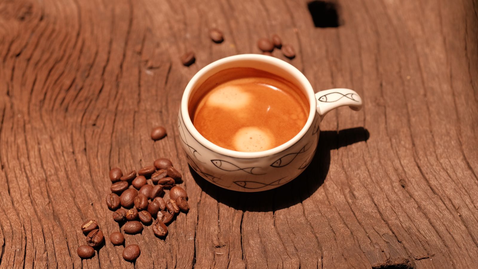 Tasse d'expresso et grains de café sur une table en bois
