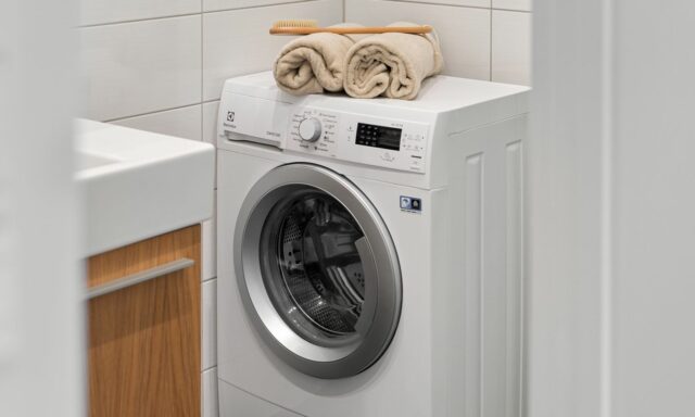 Lave-linge blanc dans une buanderie claire, serviettes posées dessus