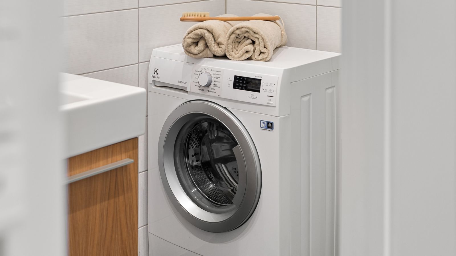 Lave-linge blanc dans une buanderie claire, serviettes posées dessus