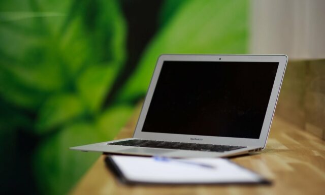 Ordinateur portable argenté ouvert sur un bureau en bois