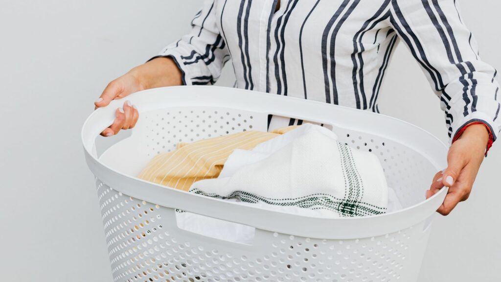 Personne portant un panier à linge rempli de linge propre