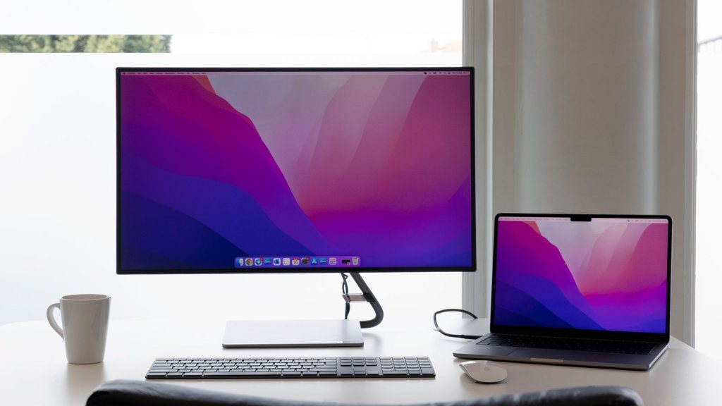 Ordinateur portable relié à un grand écran externe sur un bureau clair