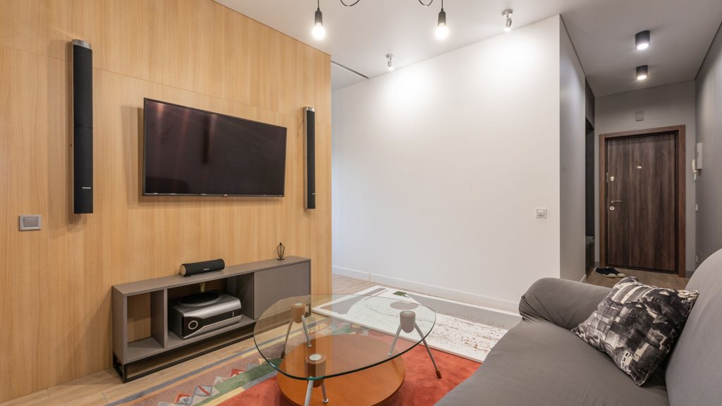 Salon contemporain avec téléviseur mural encadré de deux enceintes colonnes