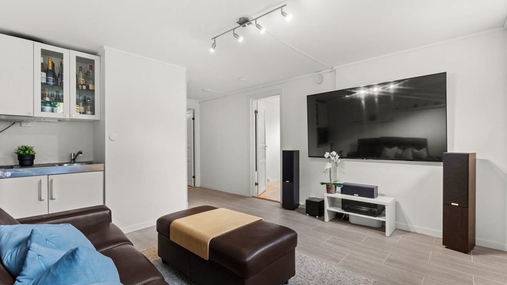 Salon spacieux avec un grand téléviseur face à un canapé en cuir