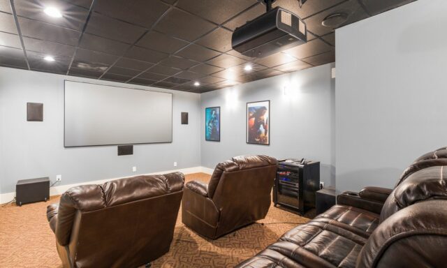 Salle home cinéma avec écran de projection et fauteuils en cuir