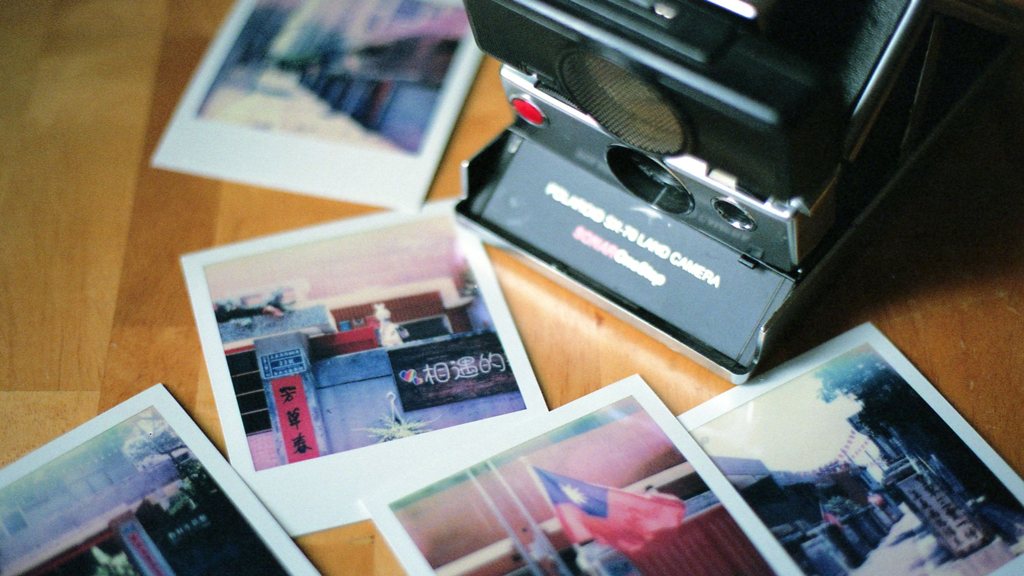 Appareil photo instantané rétro entouré de tirages sur une table en bois