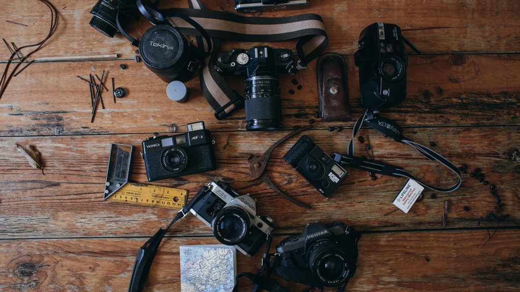 Plusieurs appareils photo anciens posés sur un plancher en bois