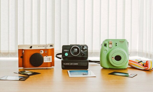 Trois appareils photo au look rétro posés sur une table avec des tirages