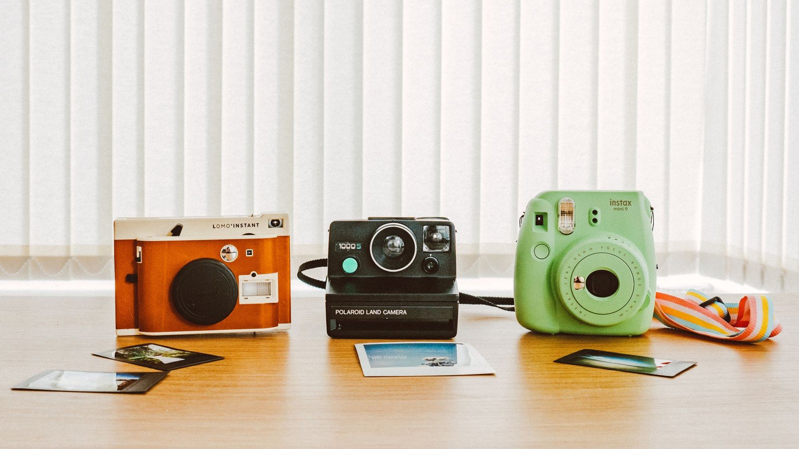 Trois appareils photo au look rétro posés sur une table avec des tirages