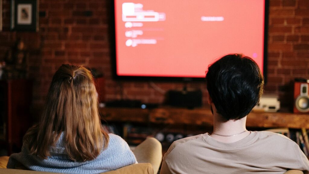Deux personnes regardant la télévision dans un salon aux murs de briques