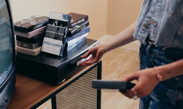 Personne installant un magnétoscope entouré de cassettes VHS