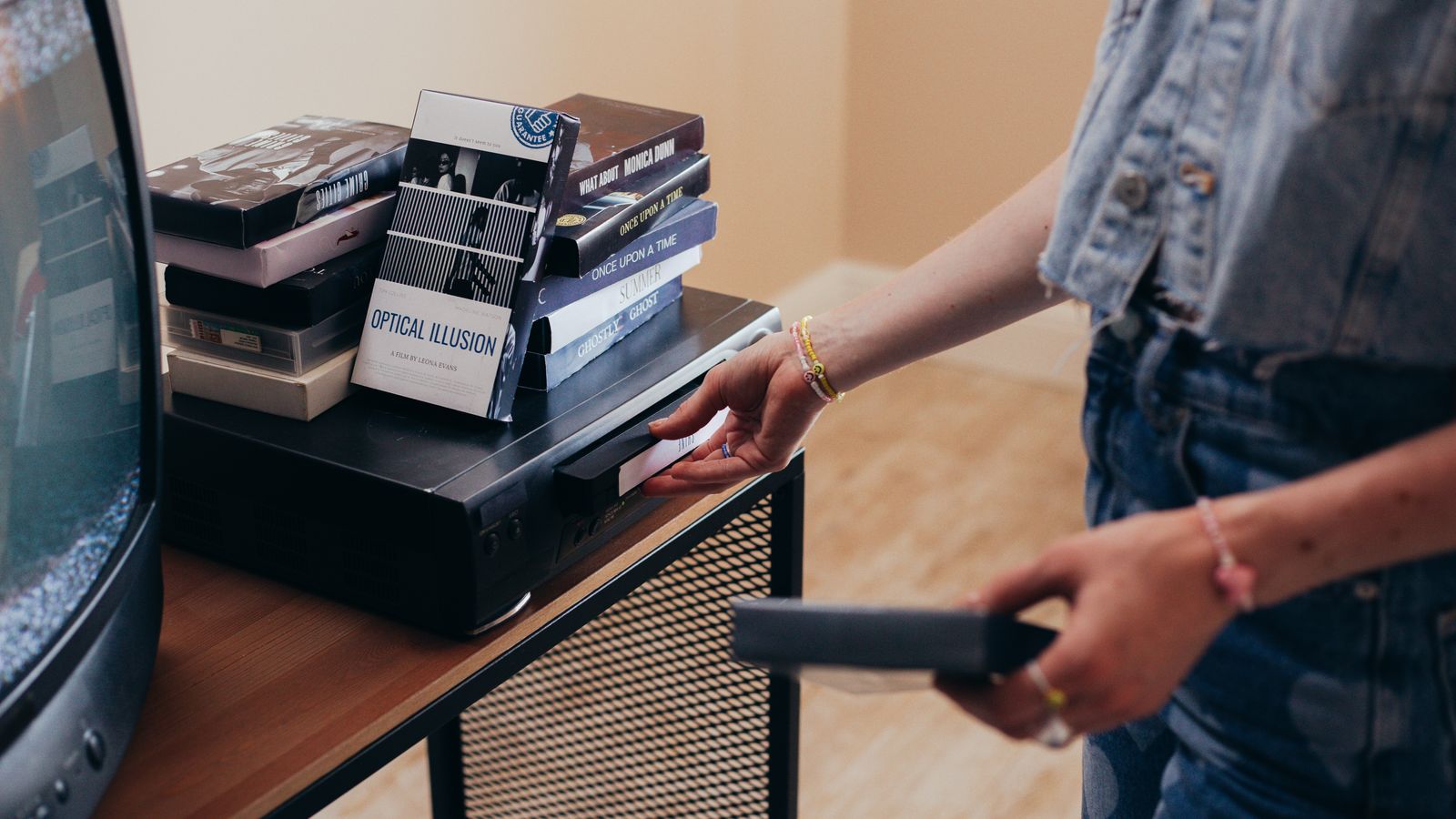 Personne installant un magnétoscope entouré de cassettes VHS