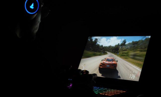 Jeu de course affiché sur un PC portable gamer dans une pièce sombre