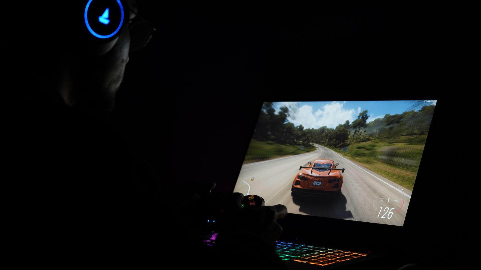 Jeu de course affiché sur un PC portable gamer dans une pièce sombre