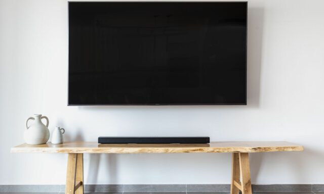 Téléviseur mural et barre de son posée sur un banc en bois
