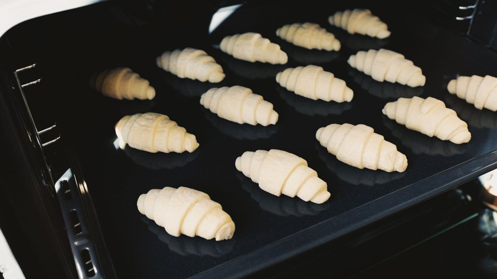Croissants crus sur une plaque enfournée dans un four