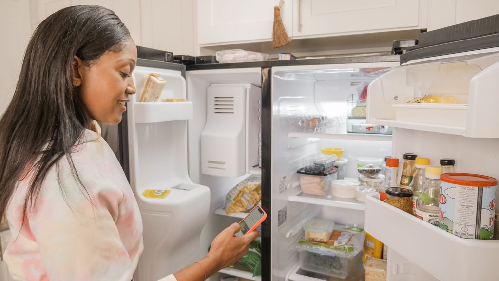 Femme devant un réfrigérateur américain side-by-side ouvert